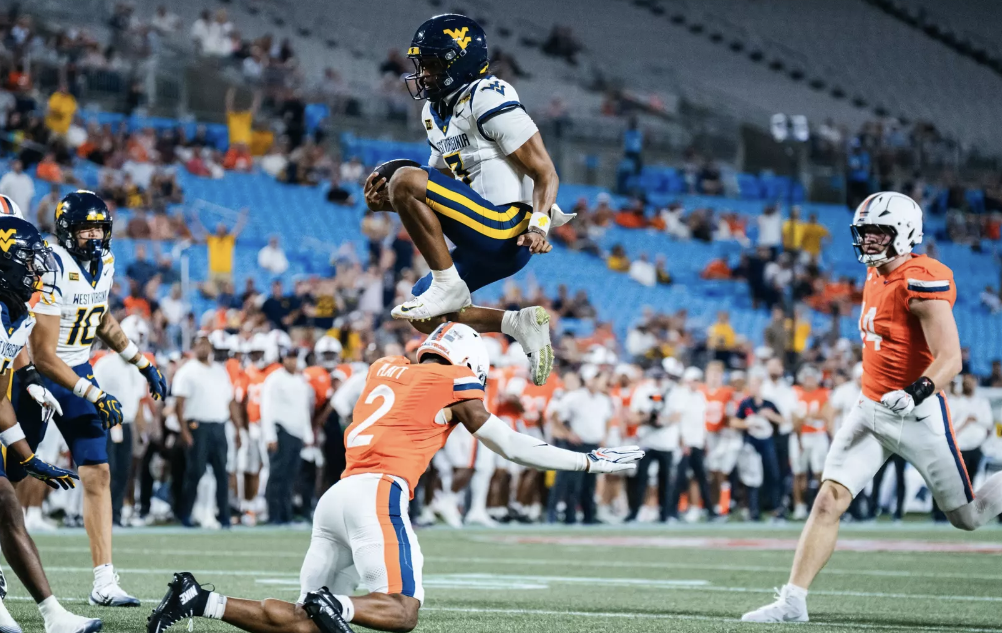 West Virginia quarterback Michael Hawkins Jr. hurdles a Virginia defender